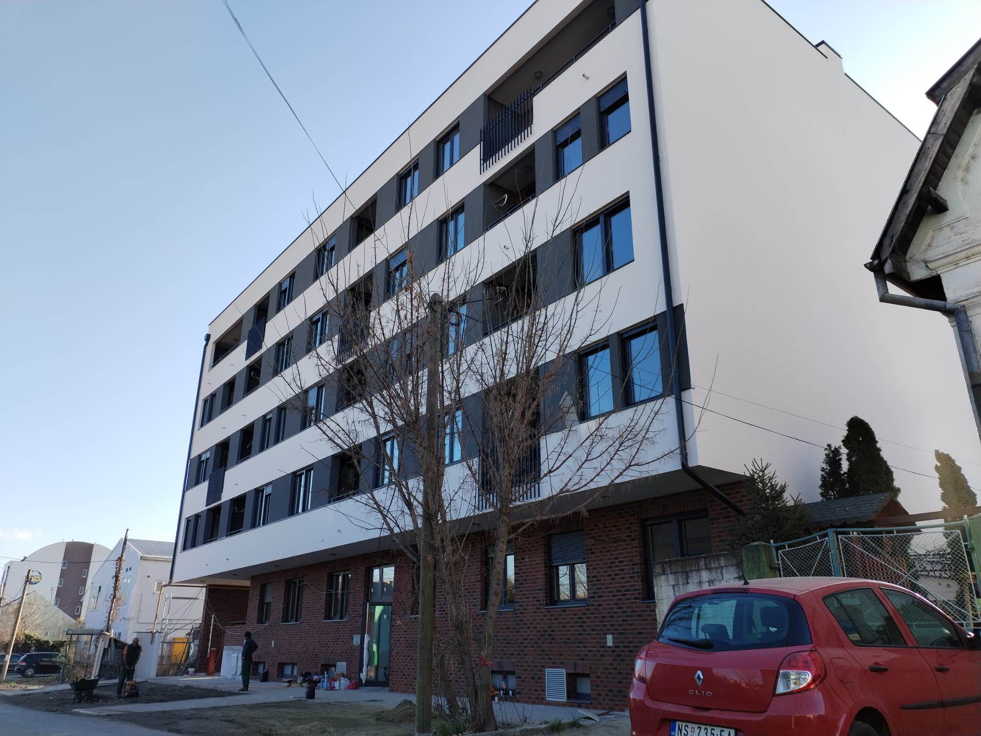 Street view of a completed residential building in Serbia with brick ground floor and rendered upper floors