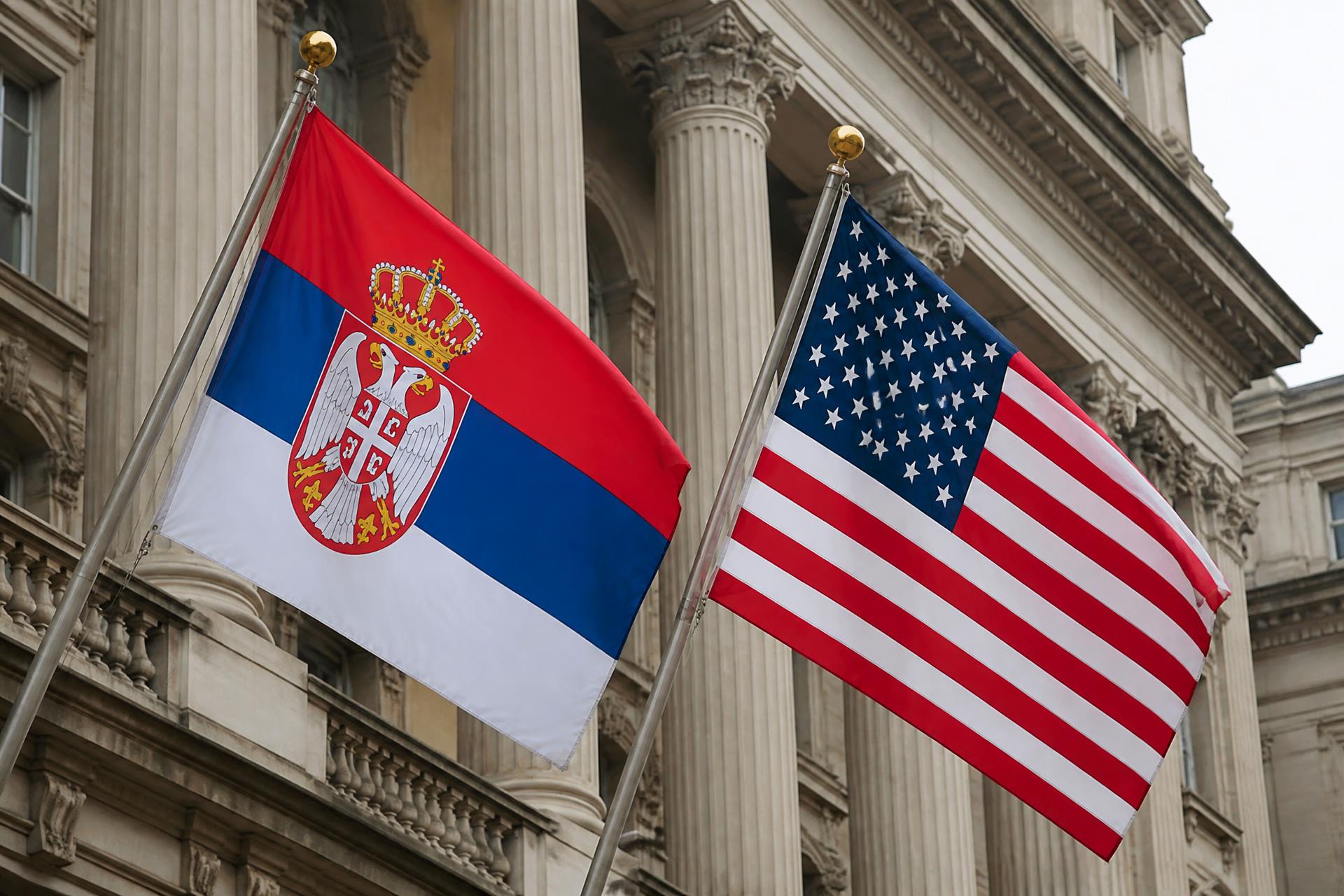 The Serbian and American flags displayed together in front of an embassy building